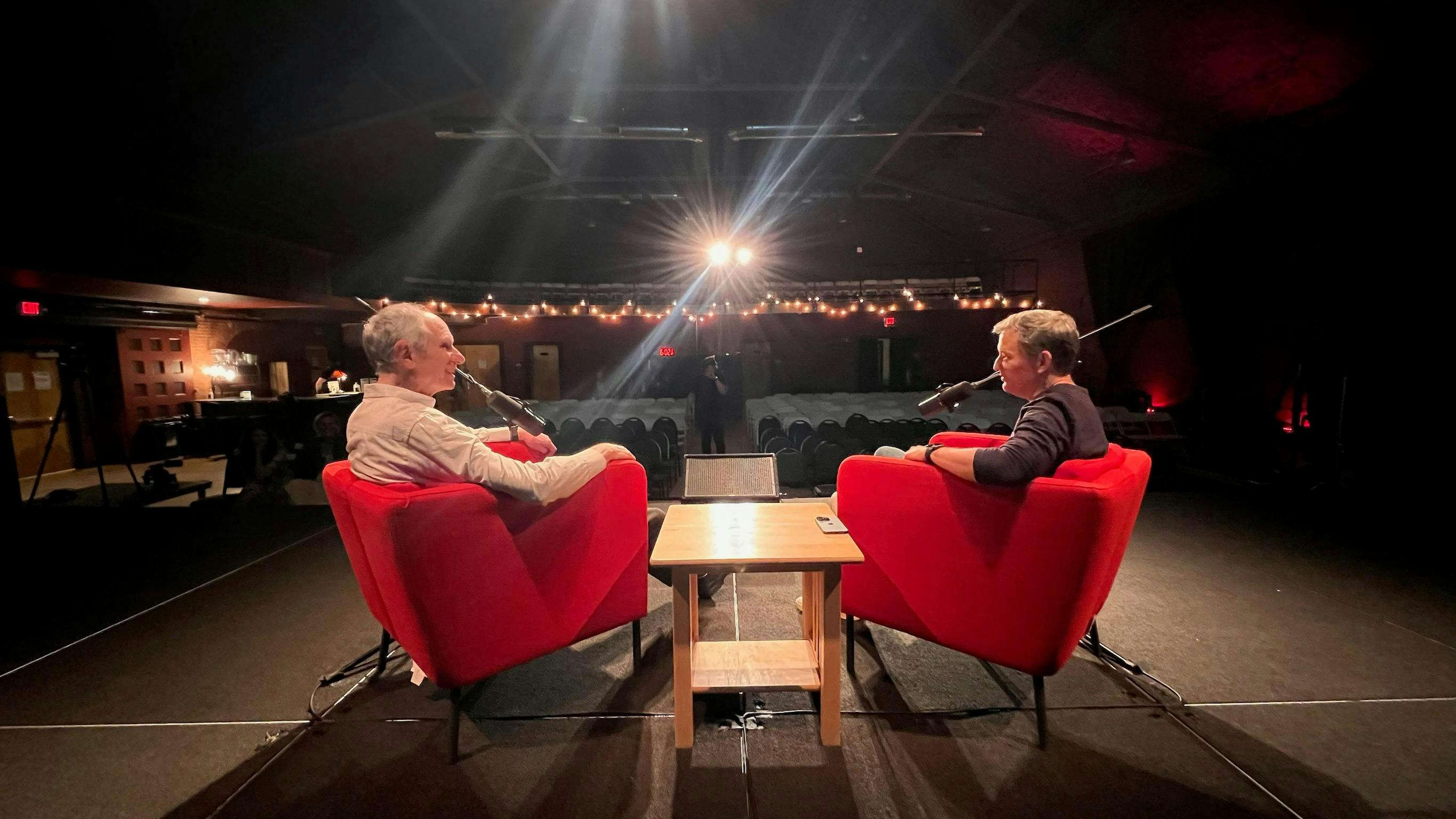 Dan Harris and Joseph Goldstein sitting in armchairs on a stage during a recording of a live podcast